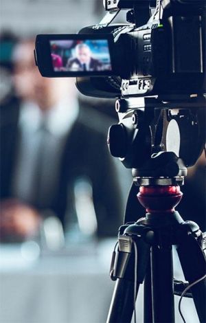 Video Camera on tripod, blurred presenter